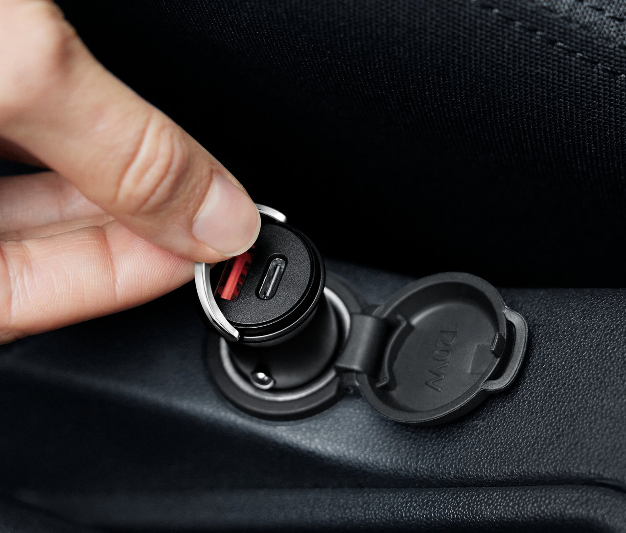 Ręka podłącza czarną ładowarkę samochodową USB-C.