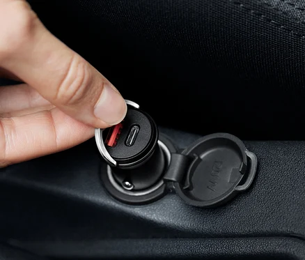 Ręka podłącza czarną ładowarkę samochodową USB-C.