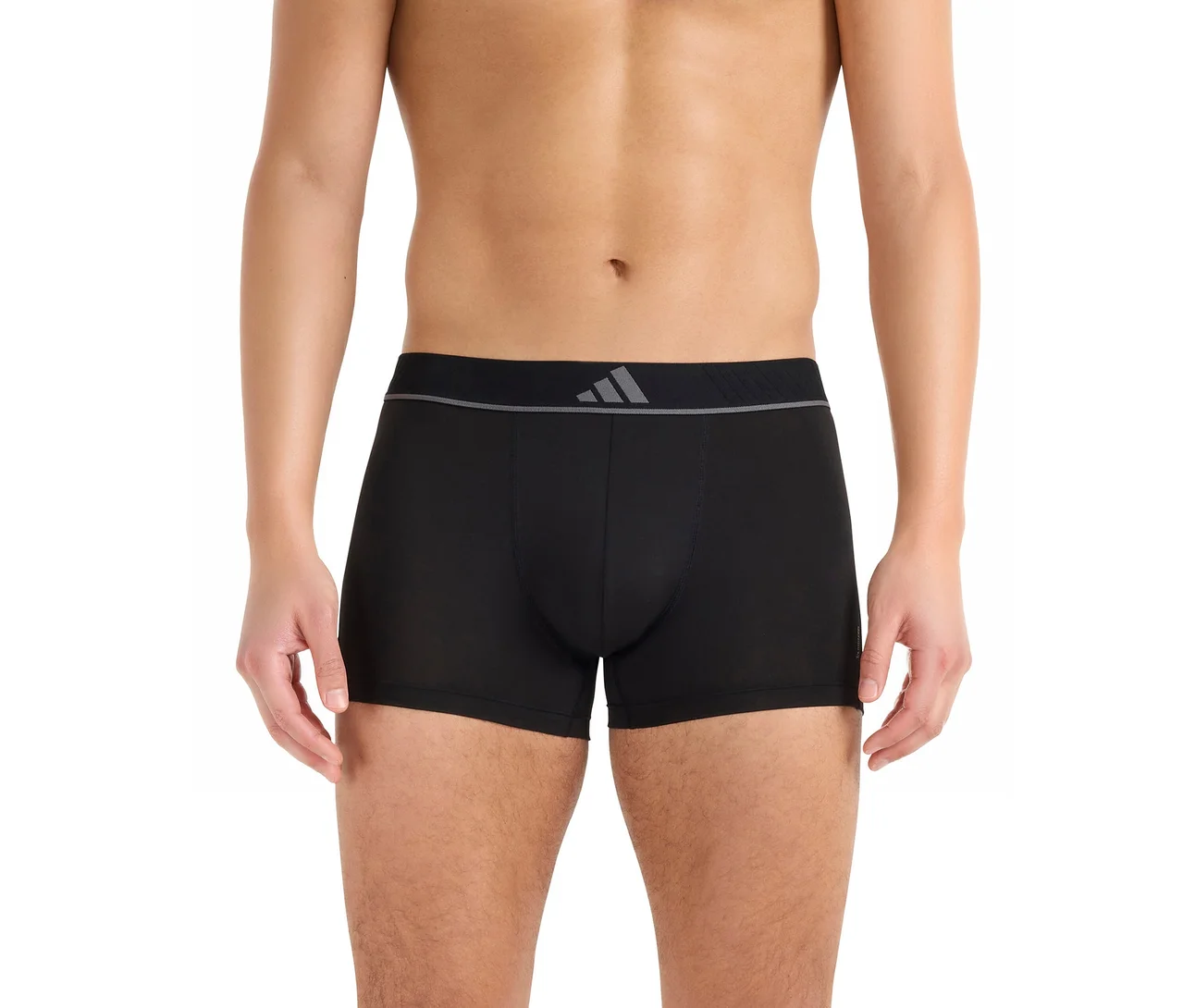 Mężczyzna w czarnych bokserkach z szarym pasem i logo Adidas, stojący bez koszulki.