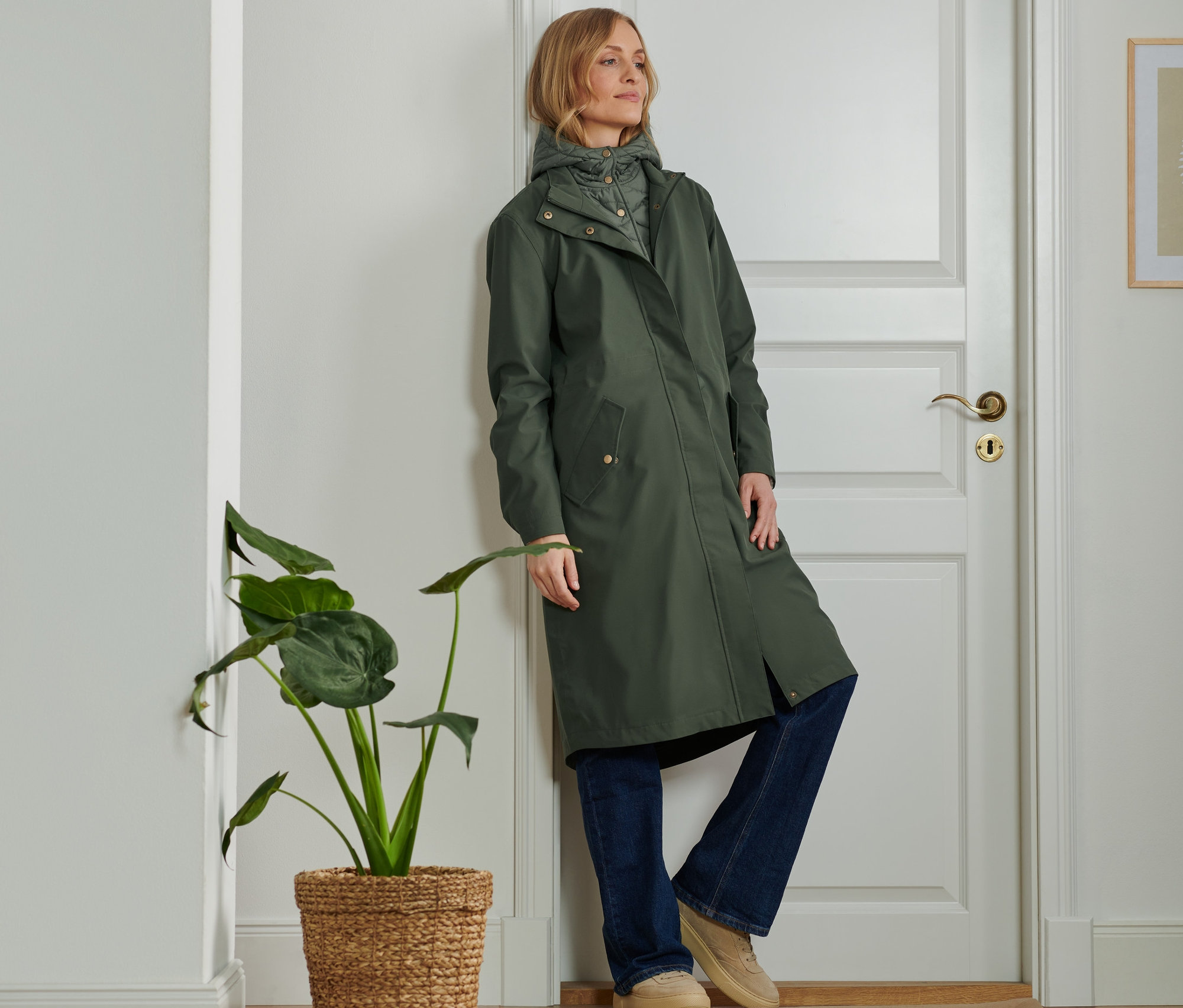 Kobieta opiera się o drzwi, ma na sobie parkę 2 w 1.