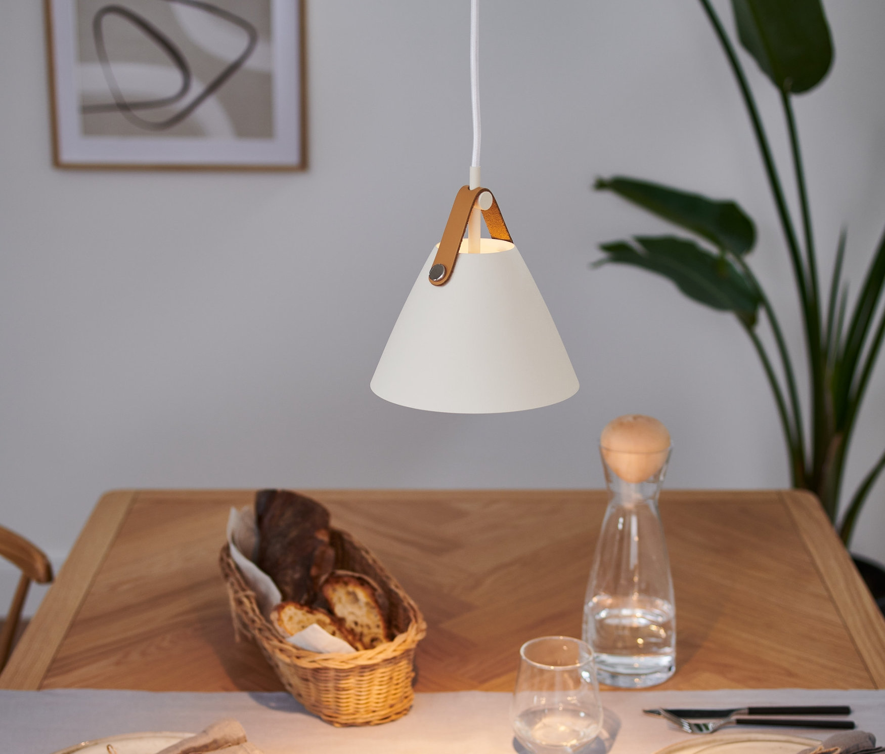 Nad stołem wisi biała lampa sufitowa »Strap 16« Design for the people by Nordlux.