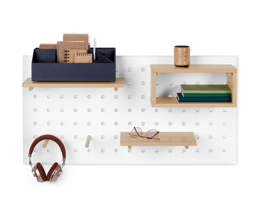 Biały panel ścienny z drewnianymi półkami, na których znajdują się przedmioty takie jak słuchawki, okulary, książki i materiały biurowe.