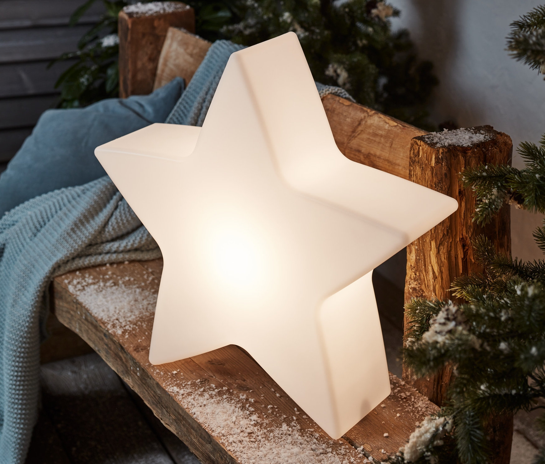 Na drewnianej ławce stoi mała solarna lampa ogrodowa »gwiazda«.