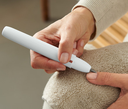 Kobieta używa urządzenia do manicure i pedicure na paznokciu.