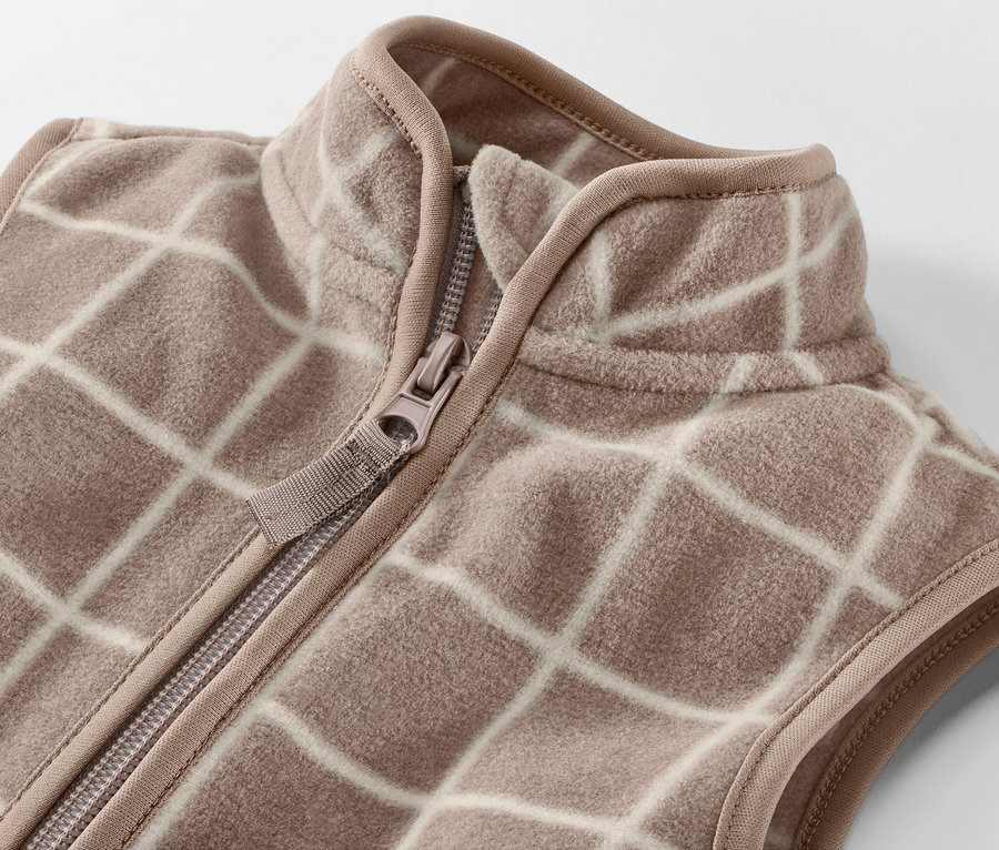 Zbliżenie na dziecięcą kamizelkę polarową w kratę z zamkiem błyskawicznym.