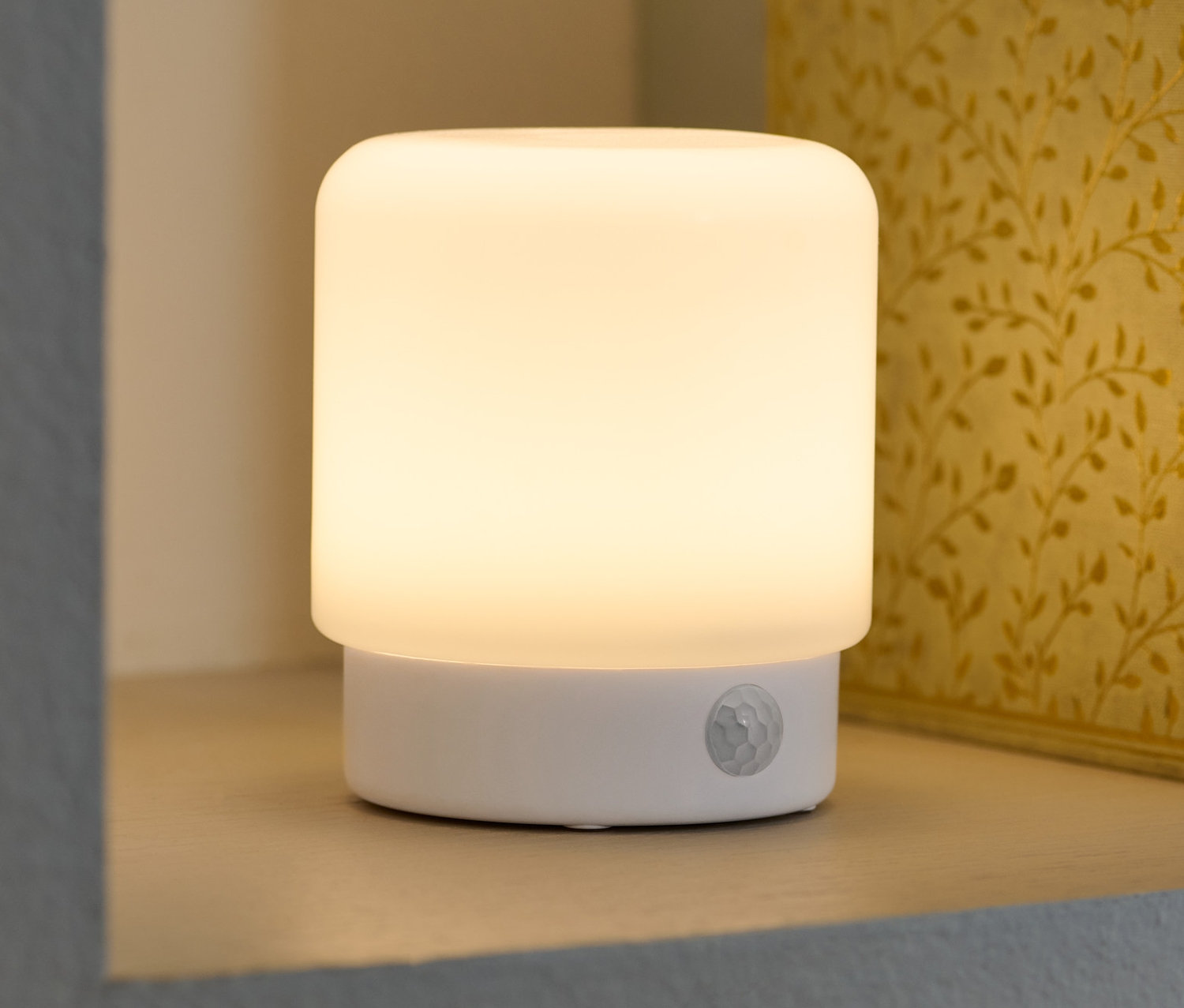 Wielofunkcyjna lampka LED z czujnikiem ruchu stoi na półce obok książek.