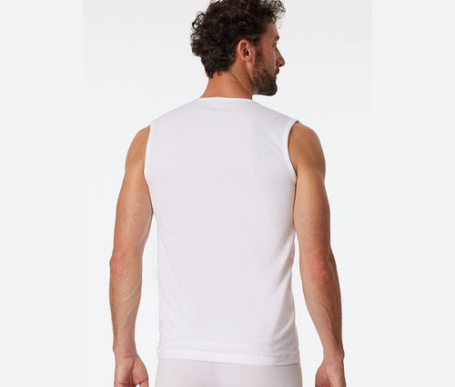 Mężczyzna tyłem do kamery ma na sobie białą podkoszulkę typu tanktop z bawełny ekologicznej SCHIESSER.