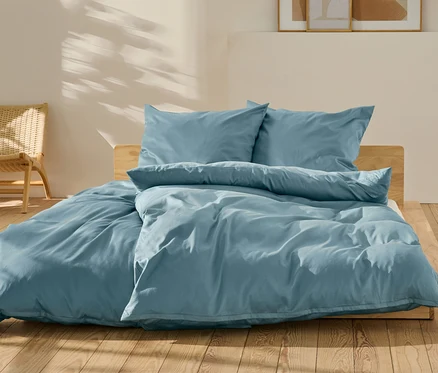 Niebieska pościel z satyny bawełnianej w standardowym i niestandardowym rozmiarze na łóżku.