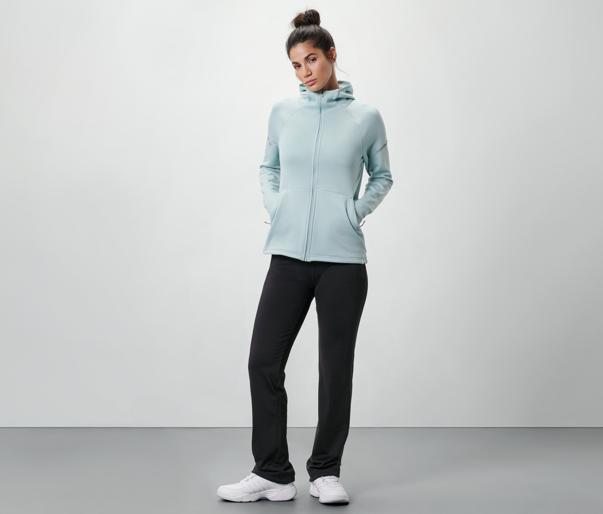 Kobieta ma na sobie spodnie termoaktywne, bluzę z kapturem i trampki.