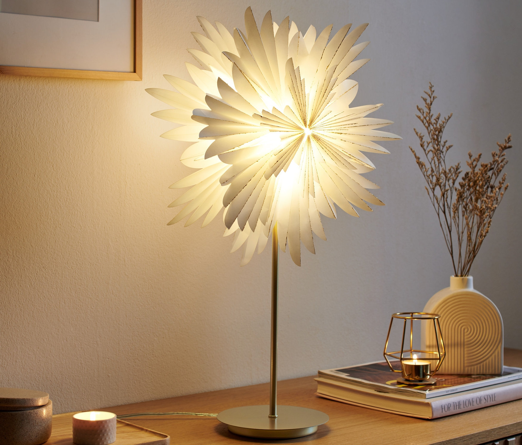 Świecąca lampa dekoracyjna LED »gwiazda« stoi na drewnianej komodzie.