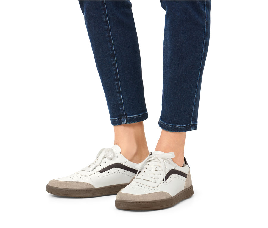 Nogi w dżinsach i skórzane sneakersy.