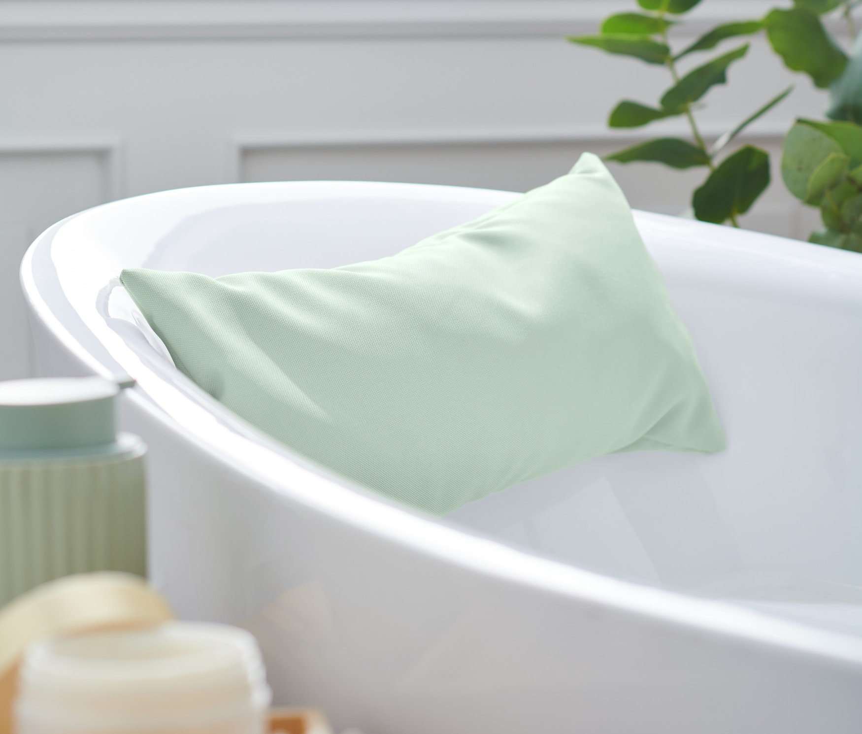 Zielona poduszka do wanny leży w białej wannie.