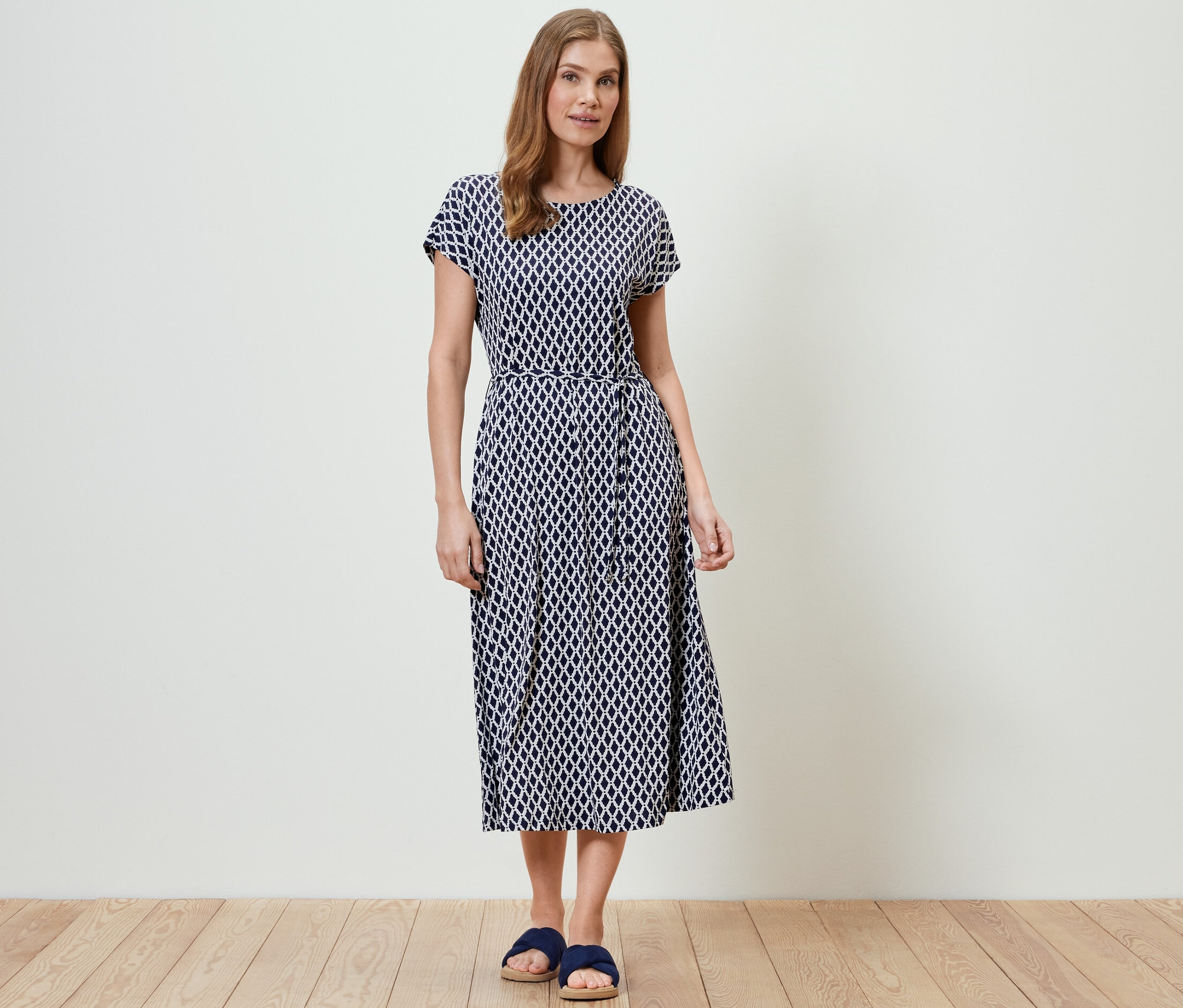 Kobieta stoi i ma na sobie wzorzystą sukienkę dżersejową.