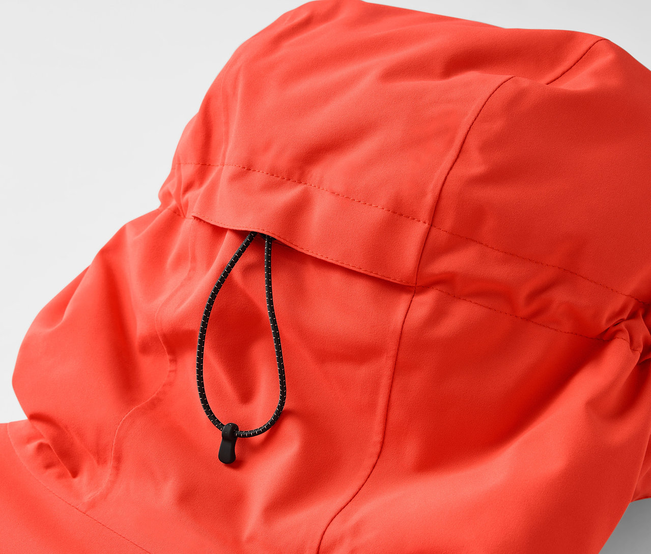 Zbliżenie na kaptur pomarańczowej kurtki ze sznurkiem.