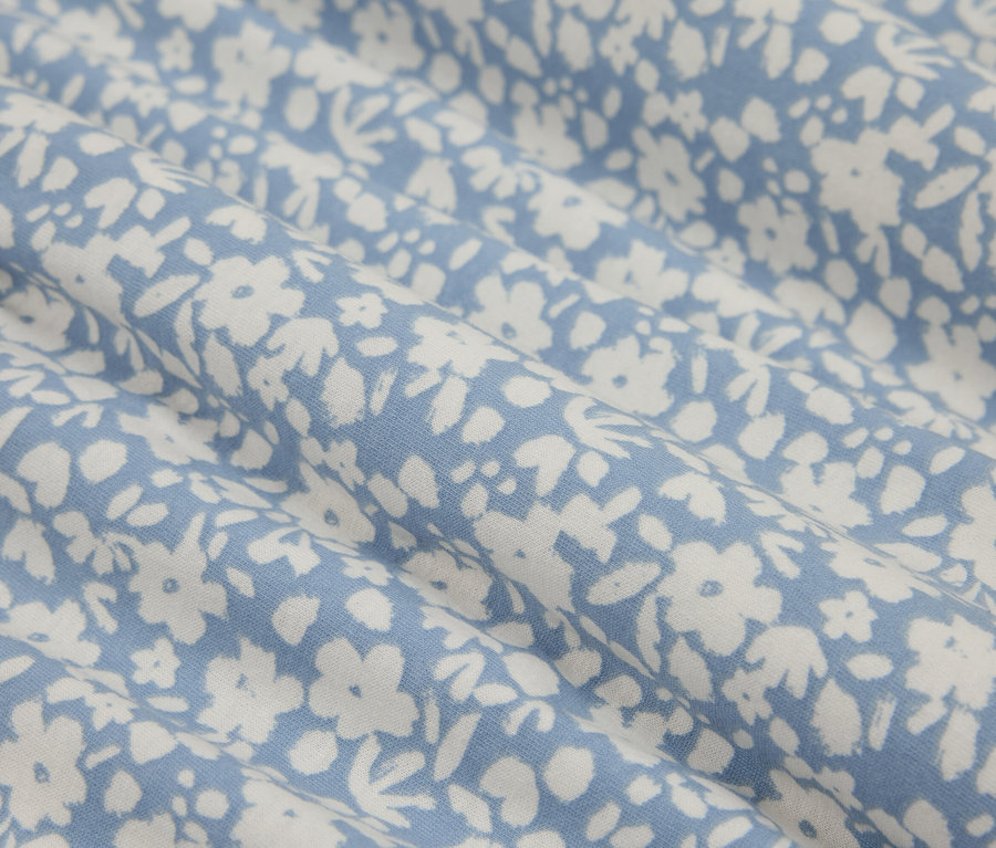 Zbliżenie na niebieską tkaninę w drobne białe kwiatki, tworzącą delikatny i świeży wzór.