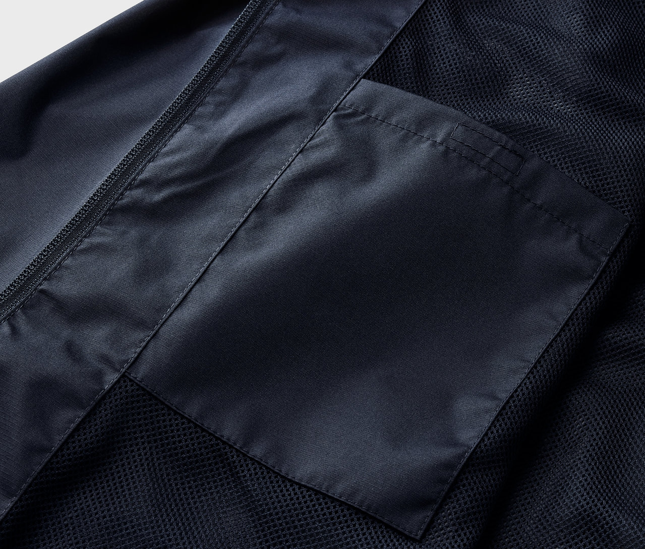 Szczegół granatowej kurtki przeciwdeszczowej z kieszenią.