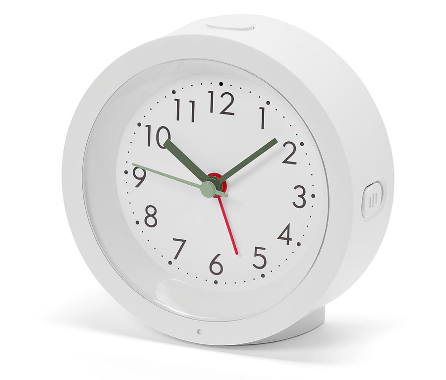 Biały budzik z analogową tarczą i zielonymi wskazówkami wskazuje godzinę.