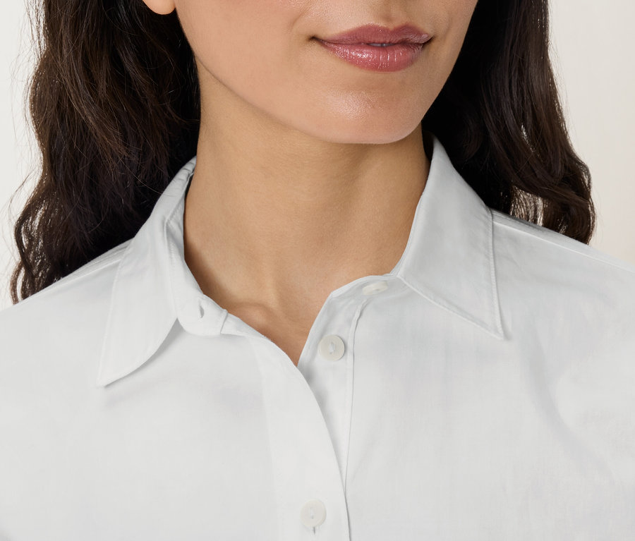 Zbliżenie na twarz i górną część ciała kobiety w białej koszuli z kołnierzykiem.