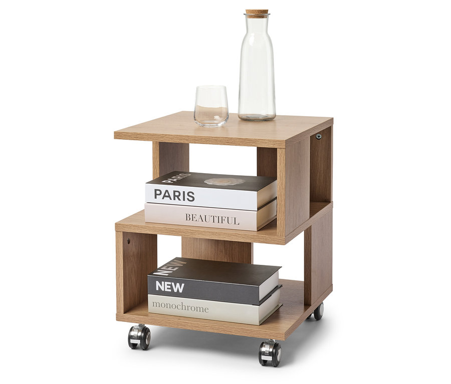 Na jasno brązowym stoliku na kółkach stoi szklanka, butelka z korkiem i dwie książki.