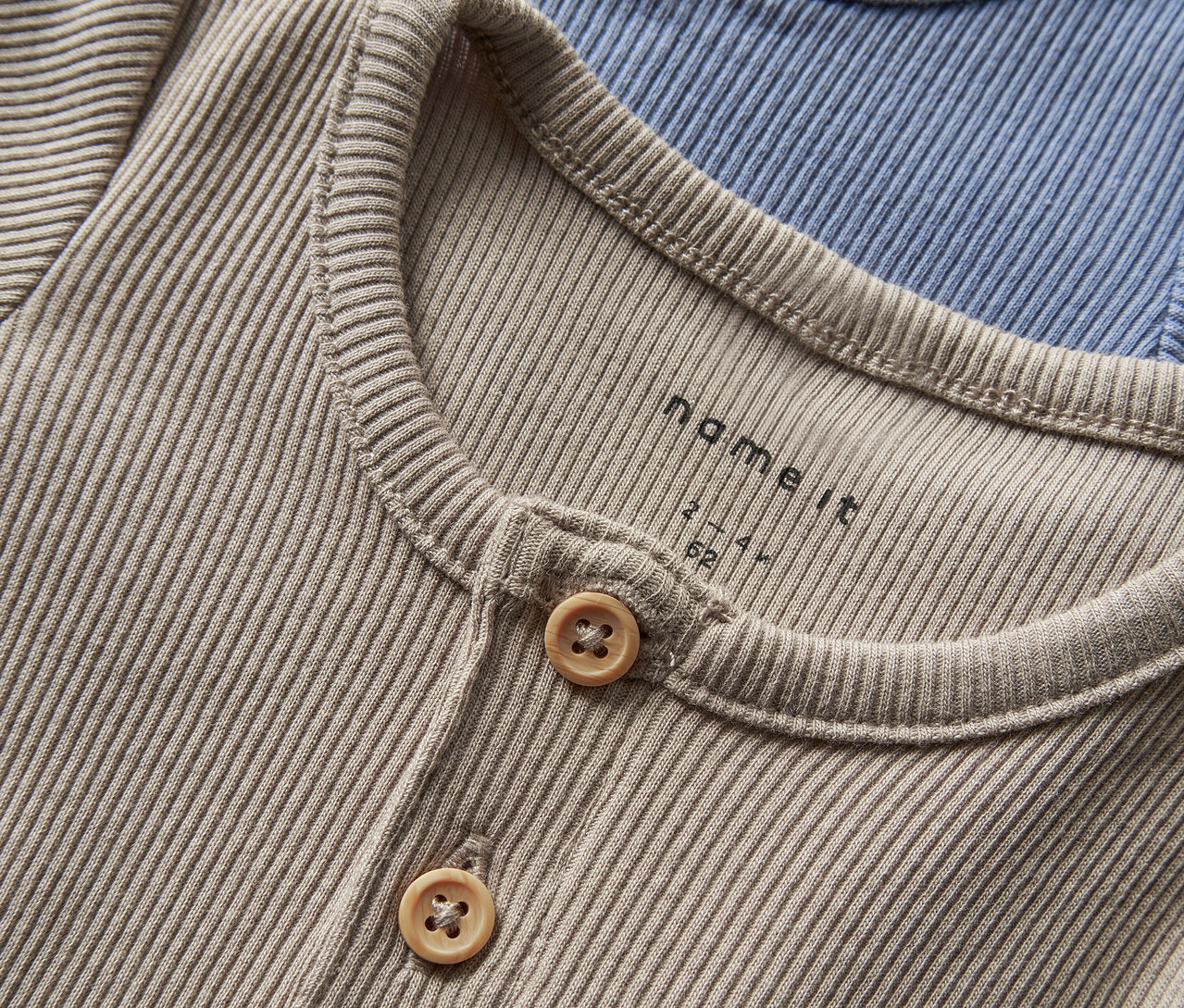 Zbliżenie na dwa body niemowlęce NAME IT, troposphere, zapinane na guziki.