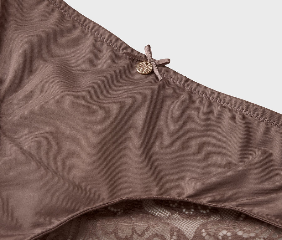 Zbliżenie na brązową bieliznę z koronkowym wykończeniem i kokardką.