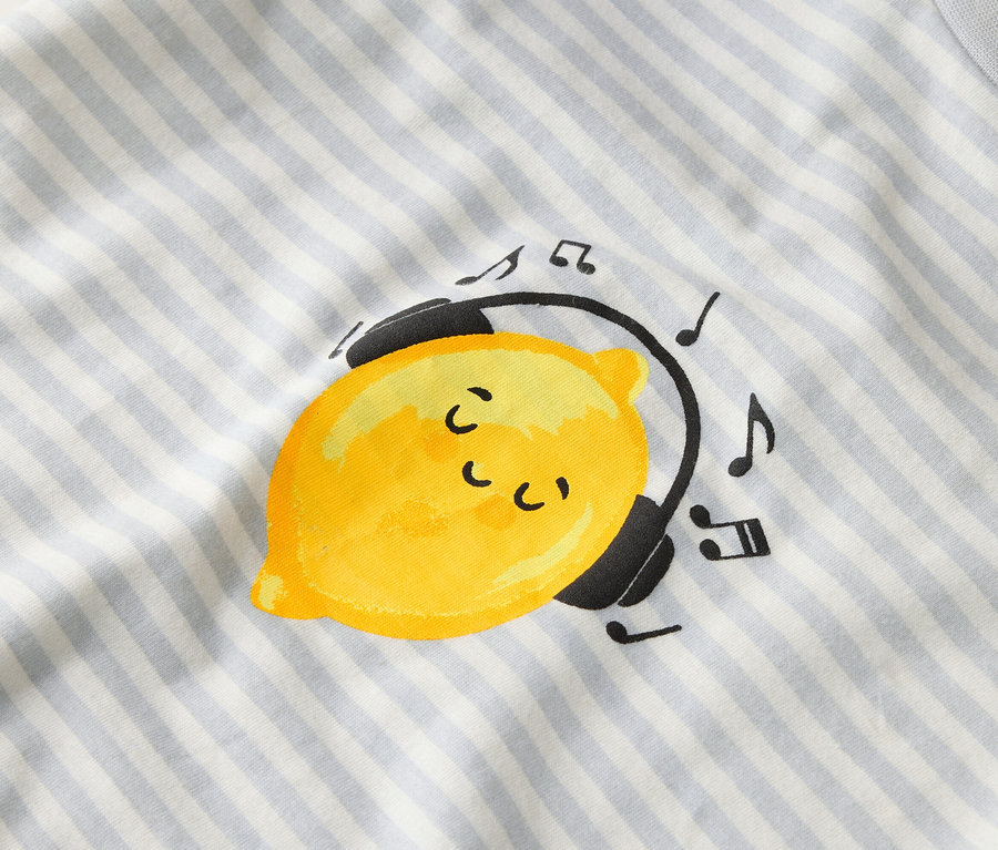 Na paskowanym materiale widnieje żółta cytryna ze słuchawkami i nutami.