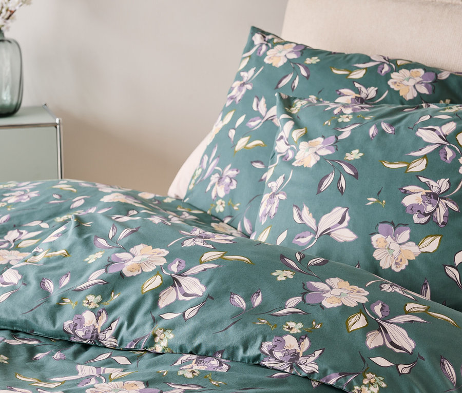 Zbliżenie pościeli w kwiaty w kolorach zielonym, fioletowym i białym.