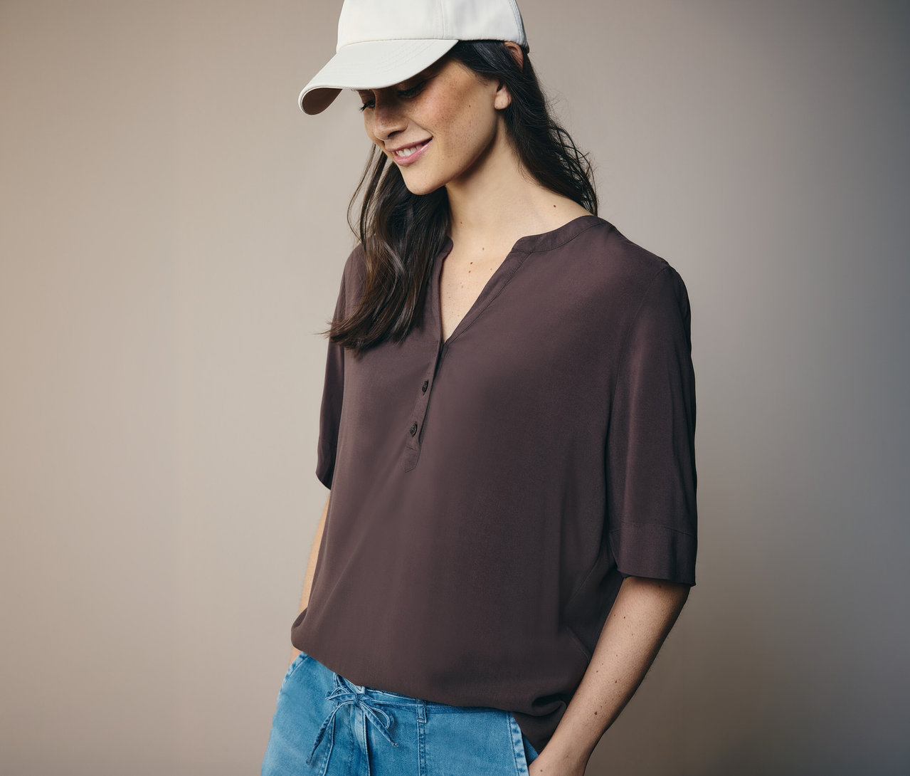 Kobieta w białej czapce i brązowej bluzce tunikowej CECIL.