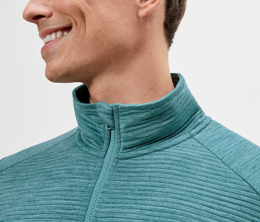 Zbliżenie mężczyzny w turkusowej bluzie polarowej zapinanej na zamek.