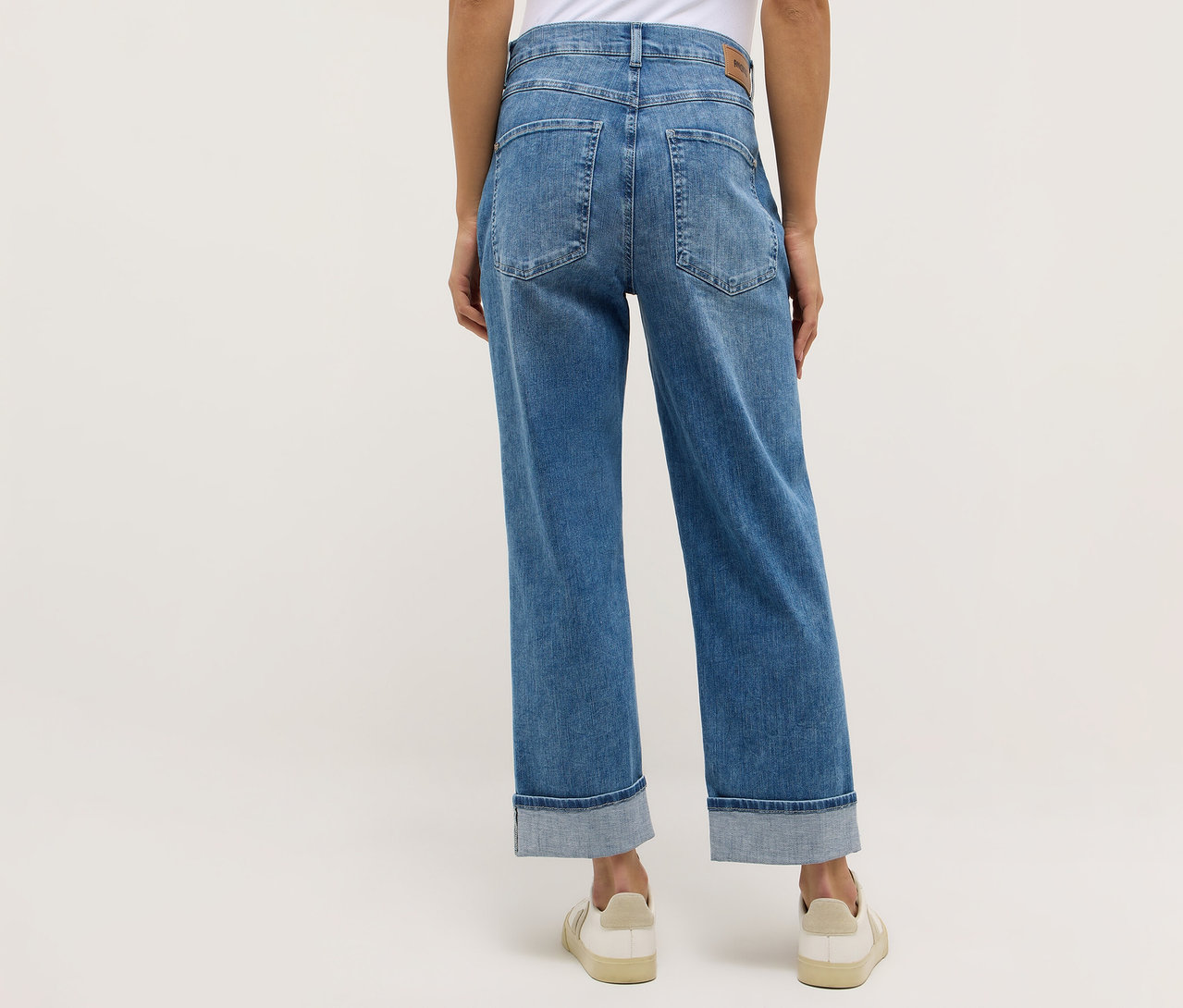 Osoba widziana od tyłu, ubrana w dżinsy Angels „Liberta” i kremowe buty.