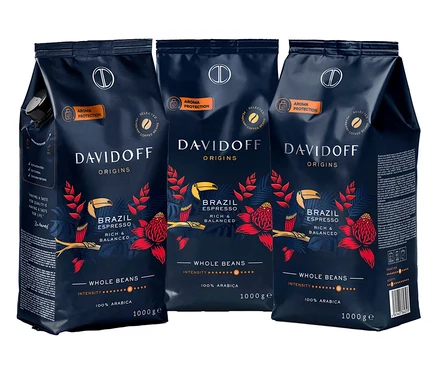 Trzy opakowania kawy Davidoff Origins Brazil Espresso w ziarnach, każde opakowanie jest ciemnoniebieskie z czerwonymi kwiatami i żółtymi ptakami.