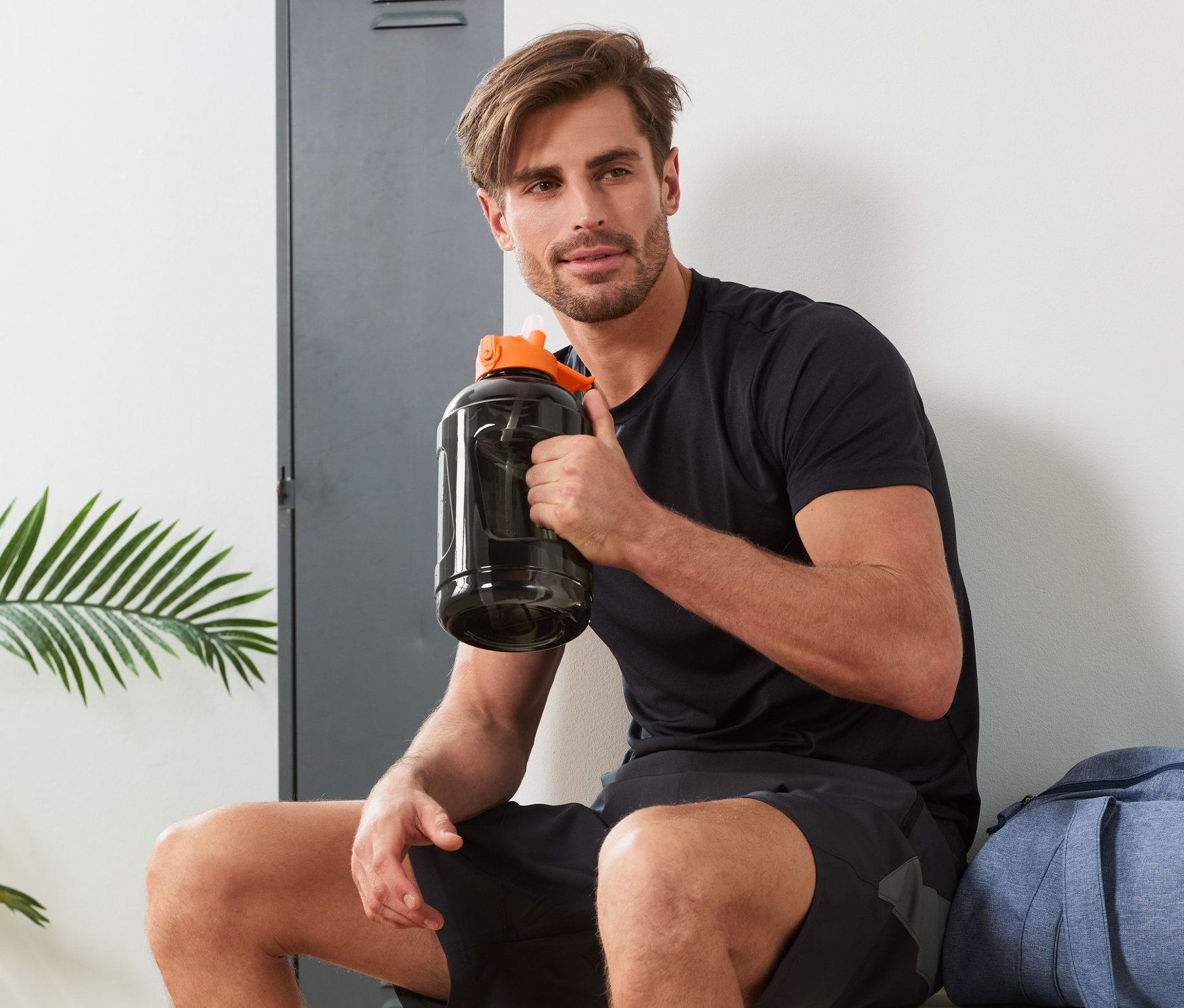 Mężczyzna siedzi i trzyma bidon XXL.