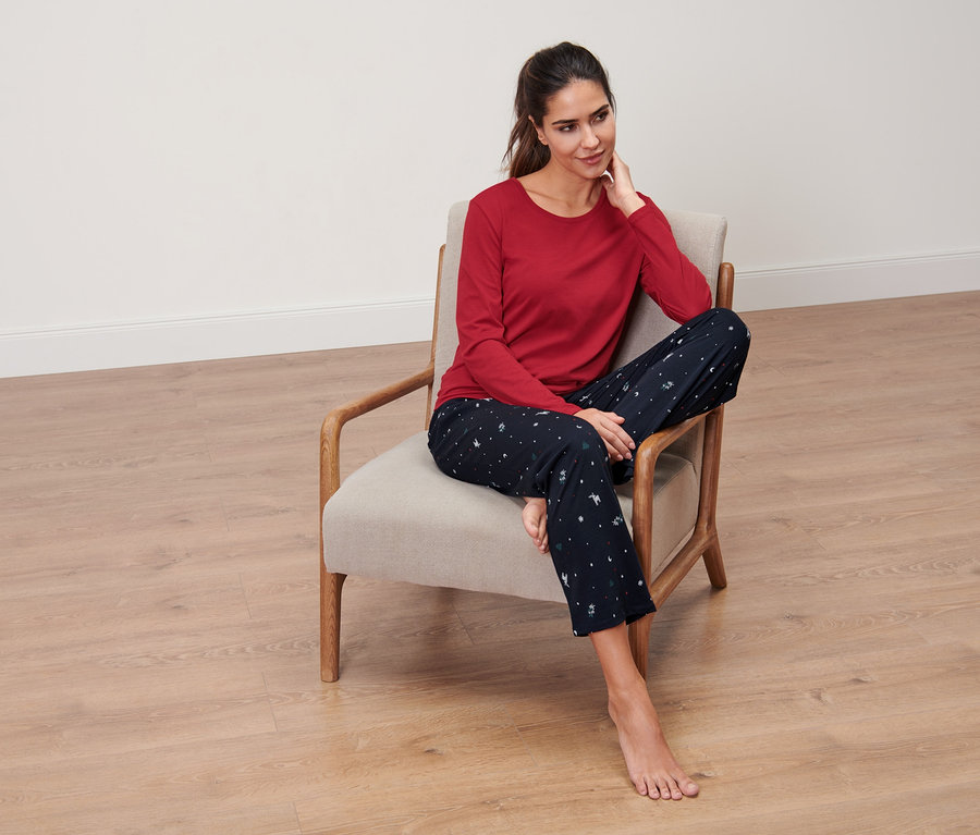 Kobieta siedzi w fotelu i ma na sobie niebieską piżamę.