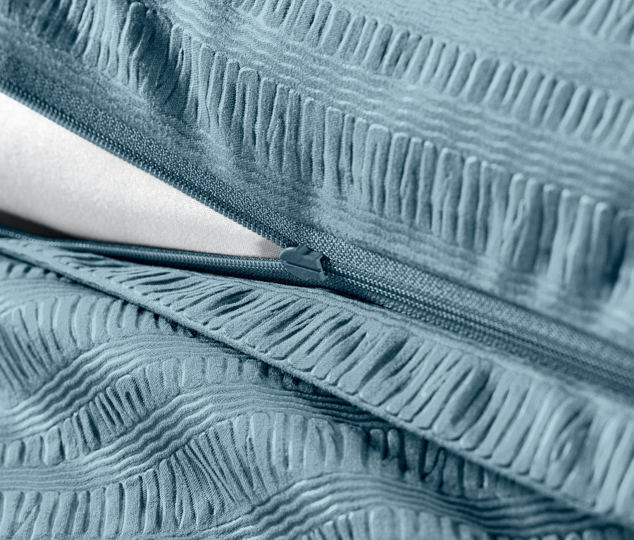 Szczegół niebieskiej pościeli z kory z zamkiem błyskawicznym i białym wypełnieniem.