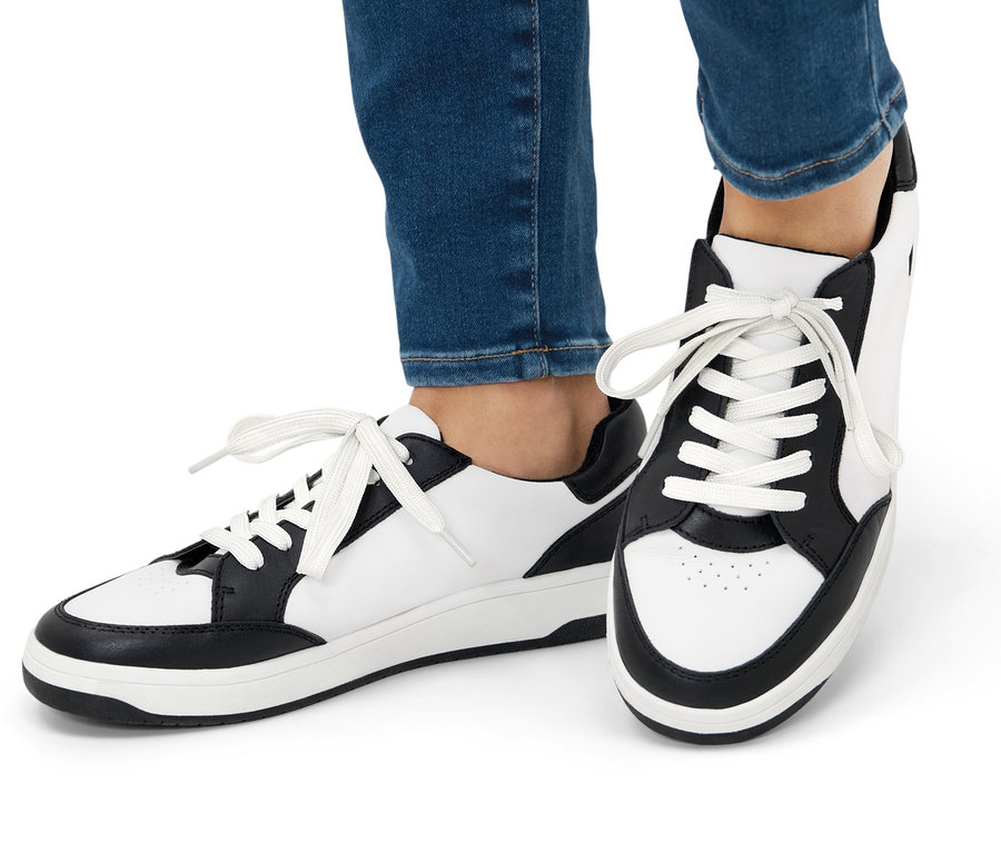 Nogi w jeansach i skórzanych sneakersach.