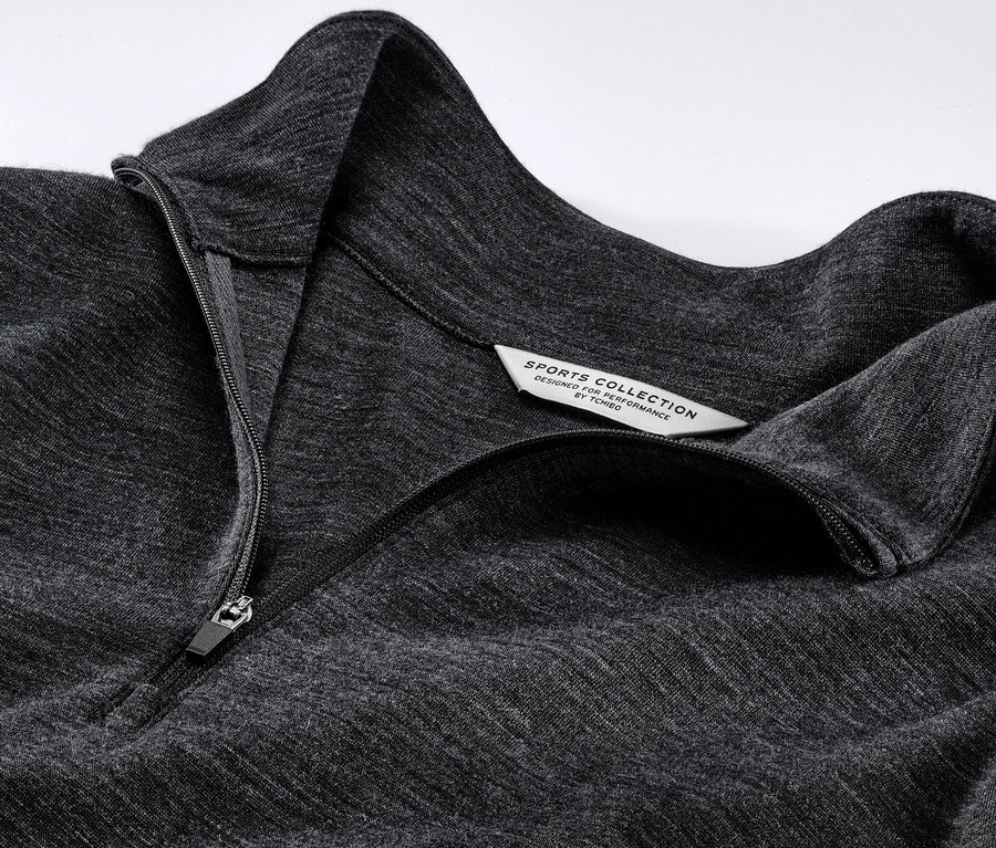 Zbliżenie na szarą koszulkę funkcyjną z wełną z certyfikatem RWS, zapinaną na zamek błyskawiczny.