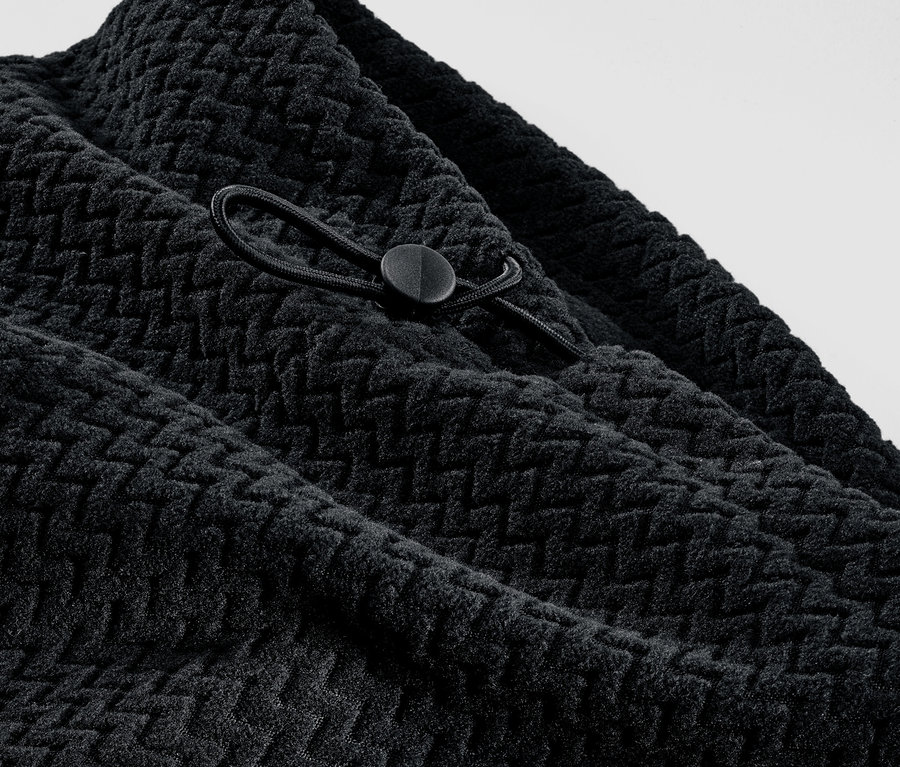 Szczegół czarnego komina z polaru z teksturą i sznurkiem.