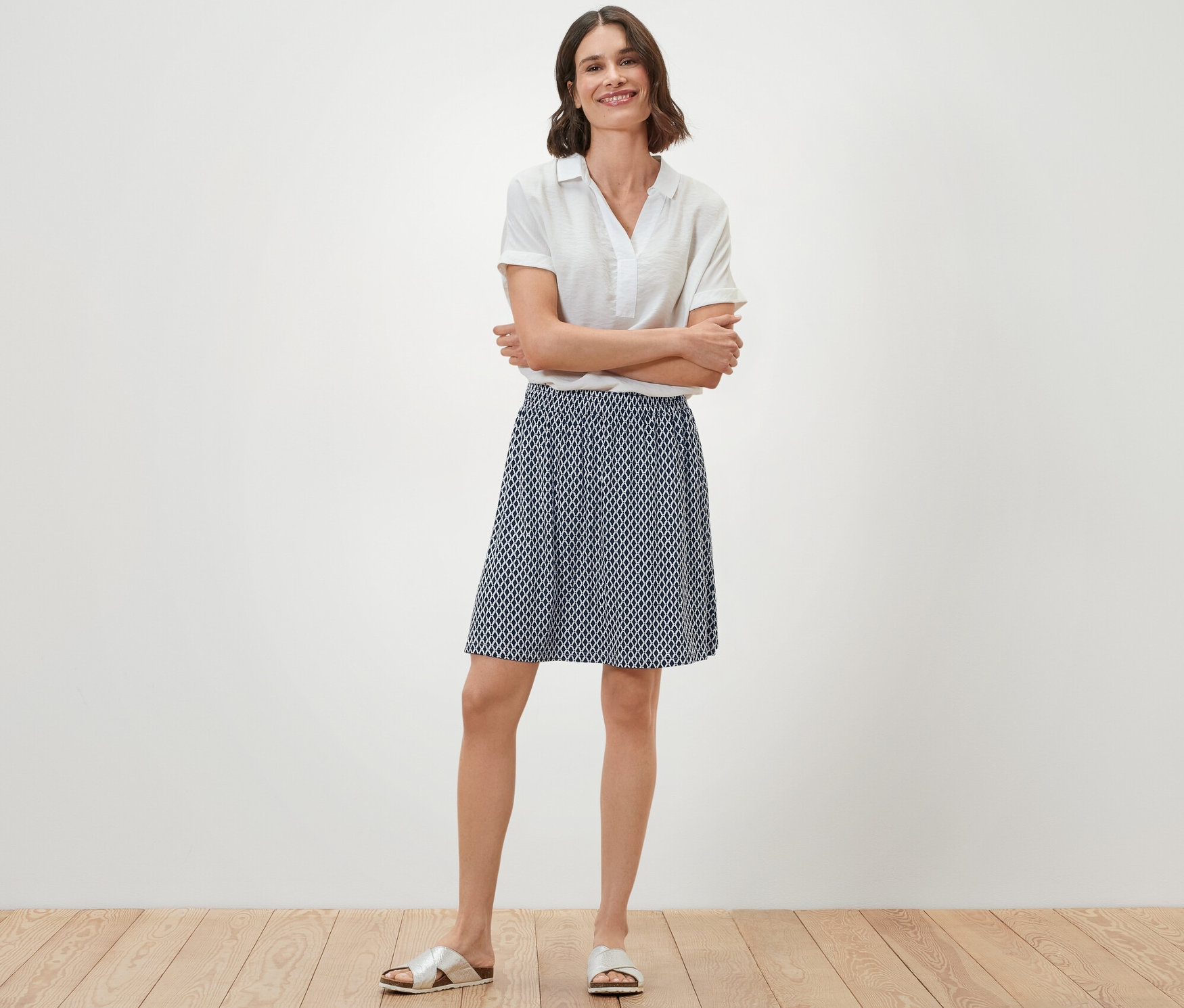 Kobieta stoi ze skrzyżowanymi ramionami, ubrana w spódnicę z dżerseju z nadrukiem.