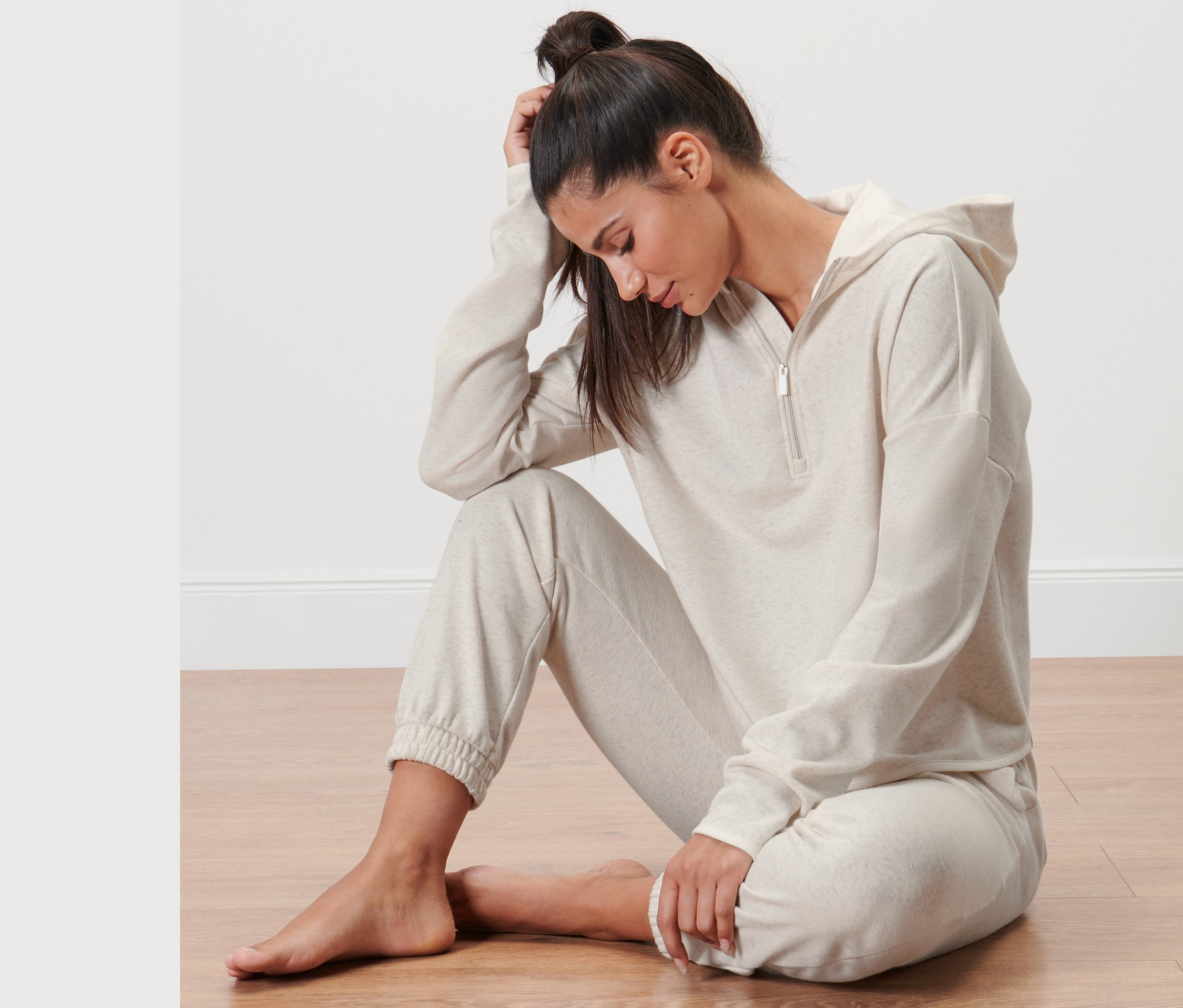 Kobieta siedzi na podłodze w bluzie z dzianiny dresowej.