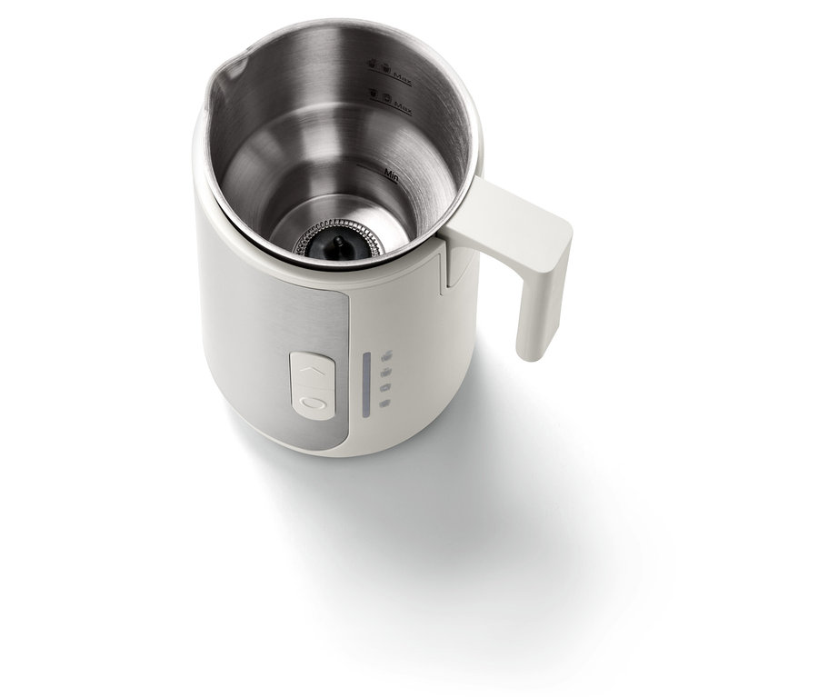 Zbliżenie na biały spieniacz do mleka z wnętrzem ze stali nierdzewnej i białym uchwytem.