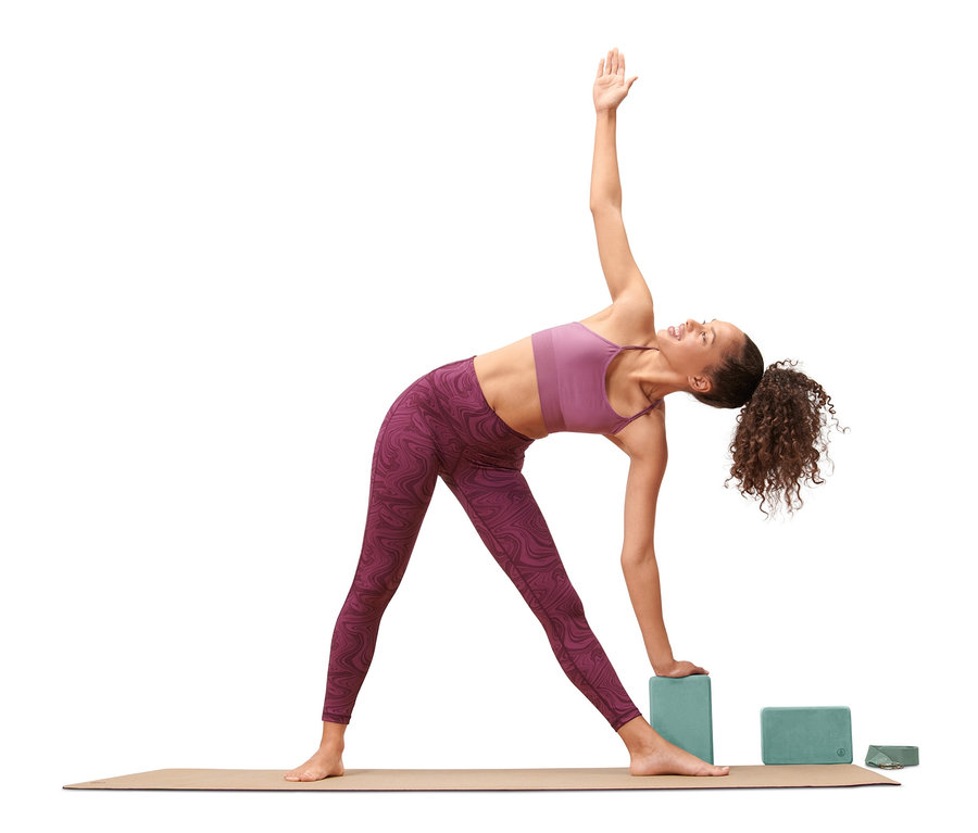 Kobieta w pozycji trójkąta w jodze, używa bloków z zestawu do jogi.