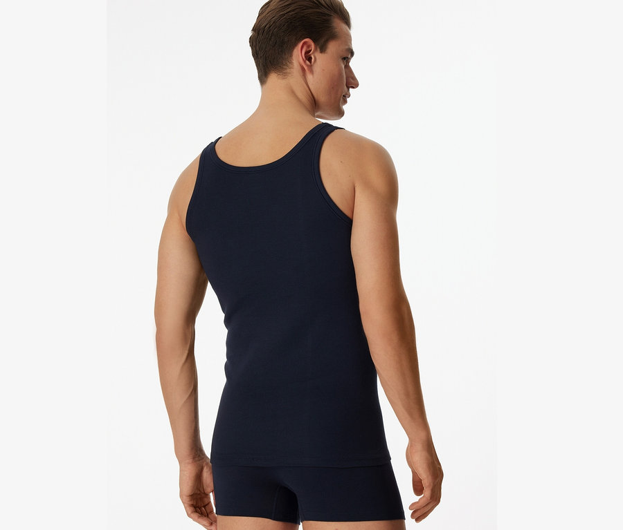 Mężczyzna od tyłu ma na sobie granatową podkoszulkę trykotową SCHIESSER, 2 sztuki.