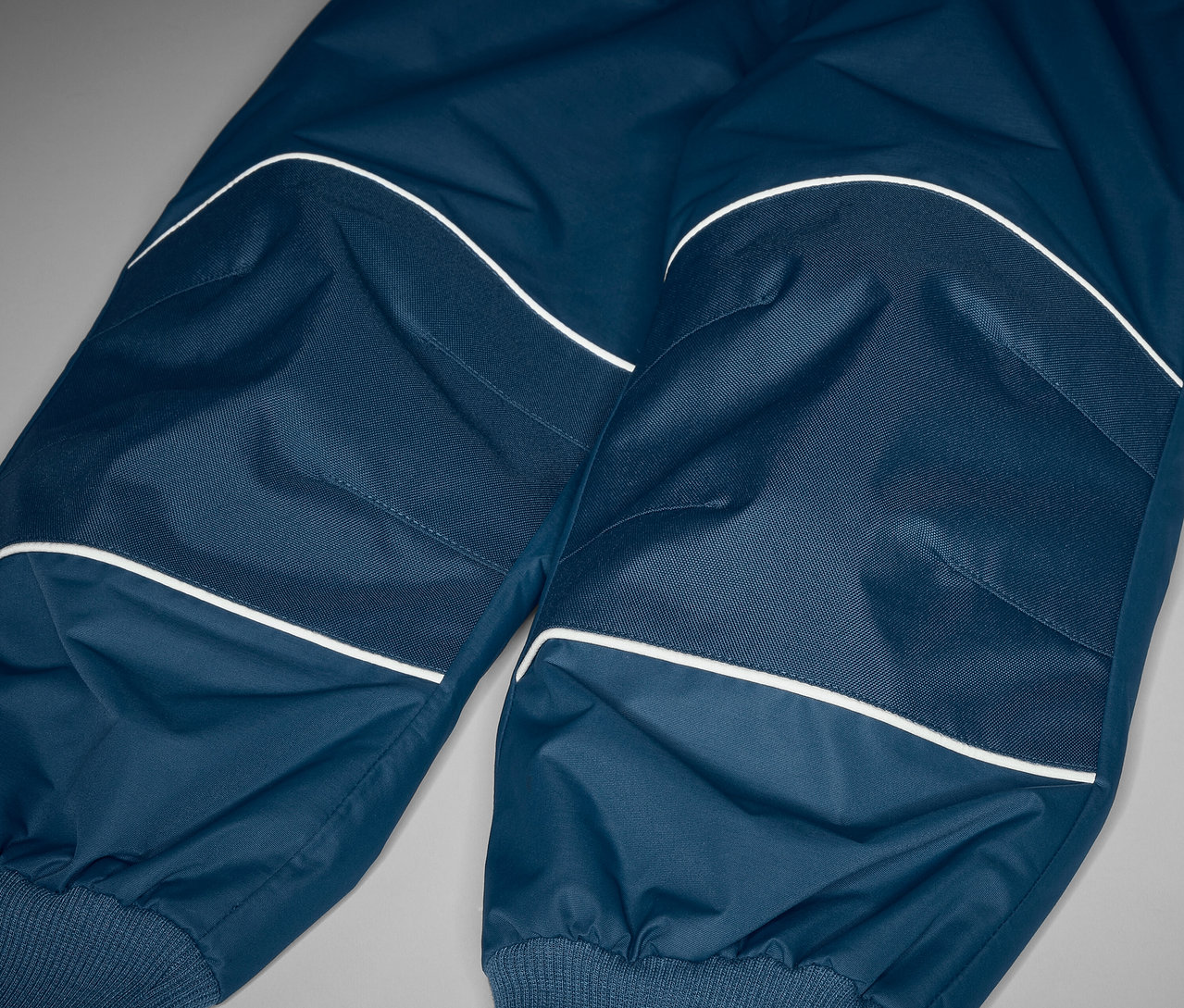 Zbliżenie na spodnie przeciwdeszczowe rosnące wraz z dzieckiem, z elementami odblaskowymi.