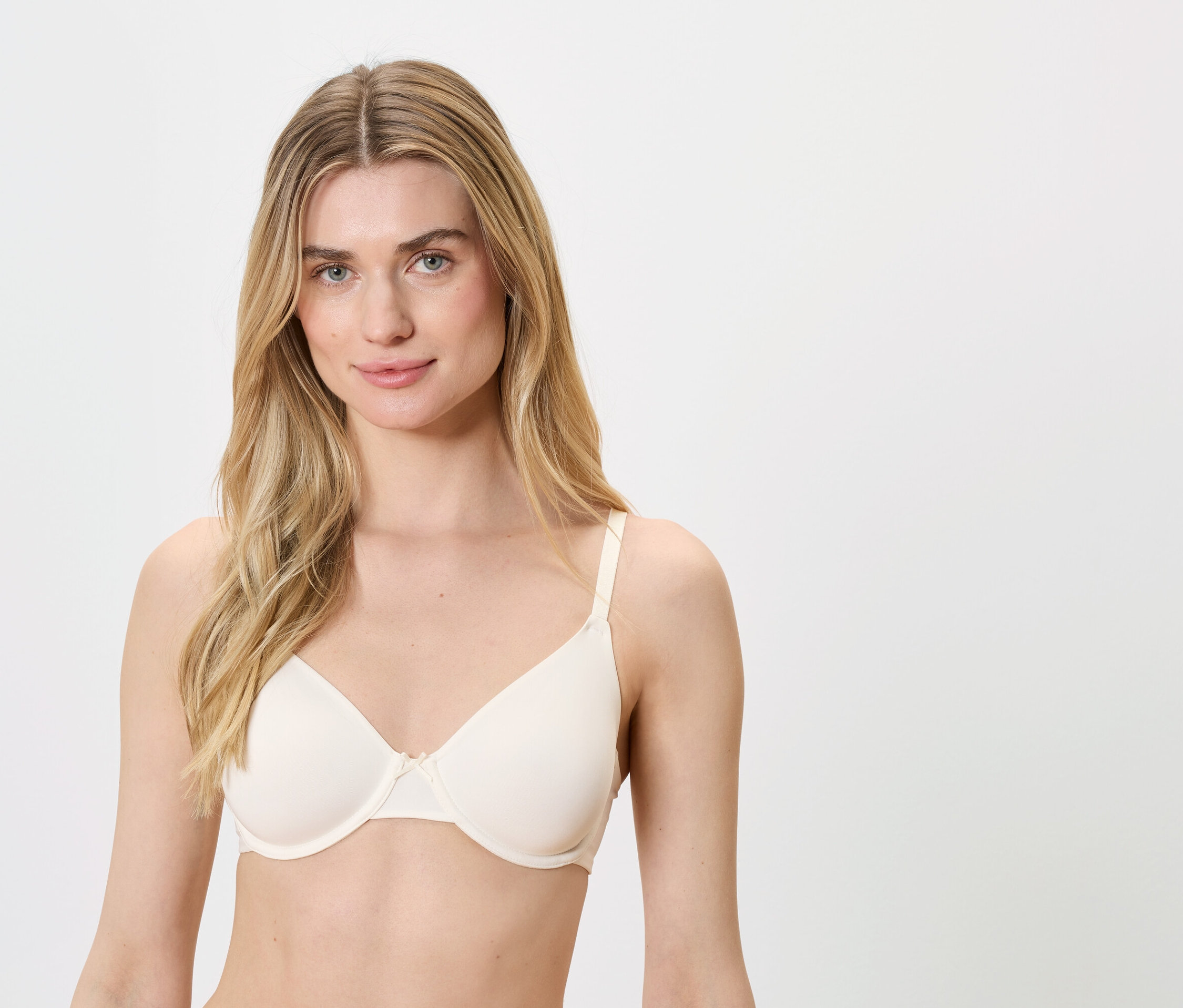 Blondynka o niebieskich oczach ma na sobie cielisty biustonosz.