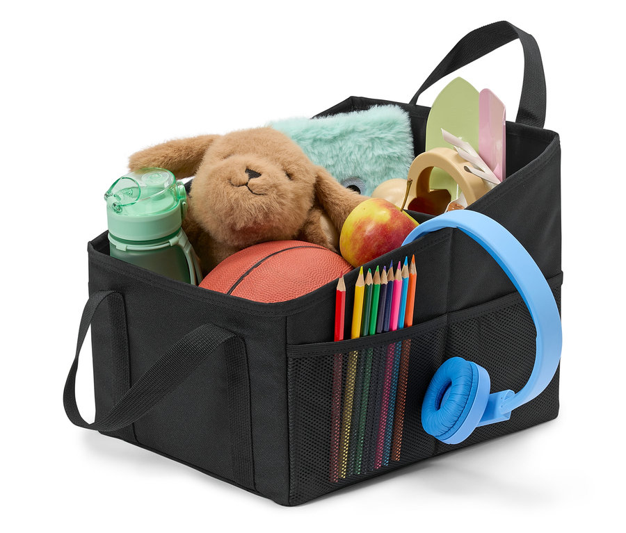 Czarny organizer wypełniony zabawkami, kredkami, słuchawkami i jabłkiem.