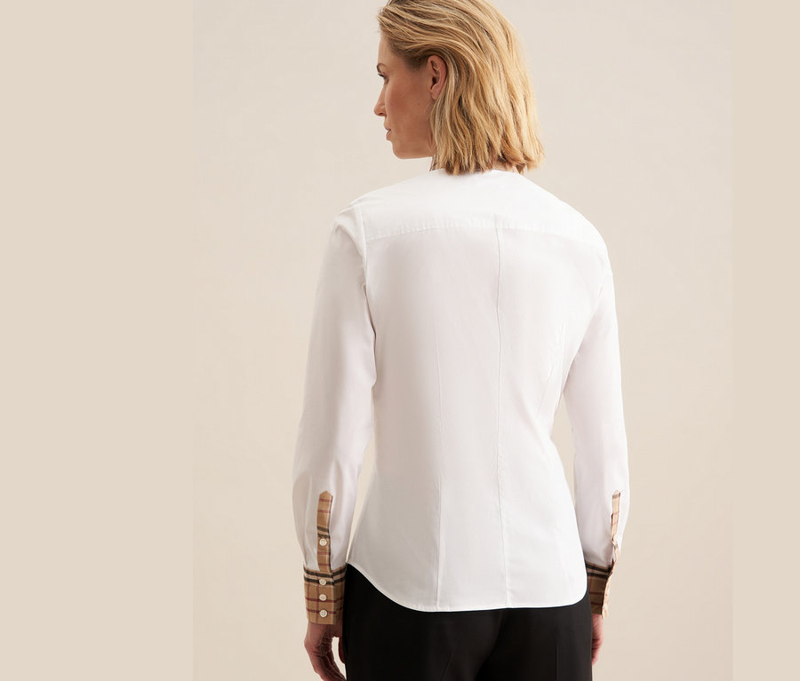 Widok z tyłu kobiety ubranej w białą popelinową koszulę Seidensticker z detalami w kratę na mankietach.