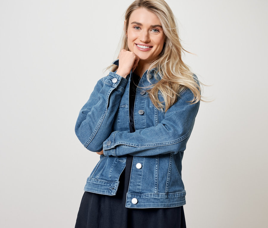 Kobieta pozuje w kurtce dżinsowej i sukience lnianej.