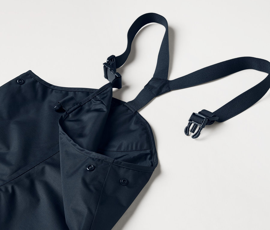 Niebieski fartuch z regulowanymi ramiączkami i naszytą kieszenią, na białym tle.