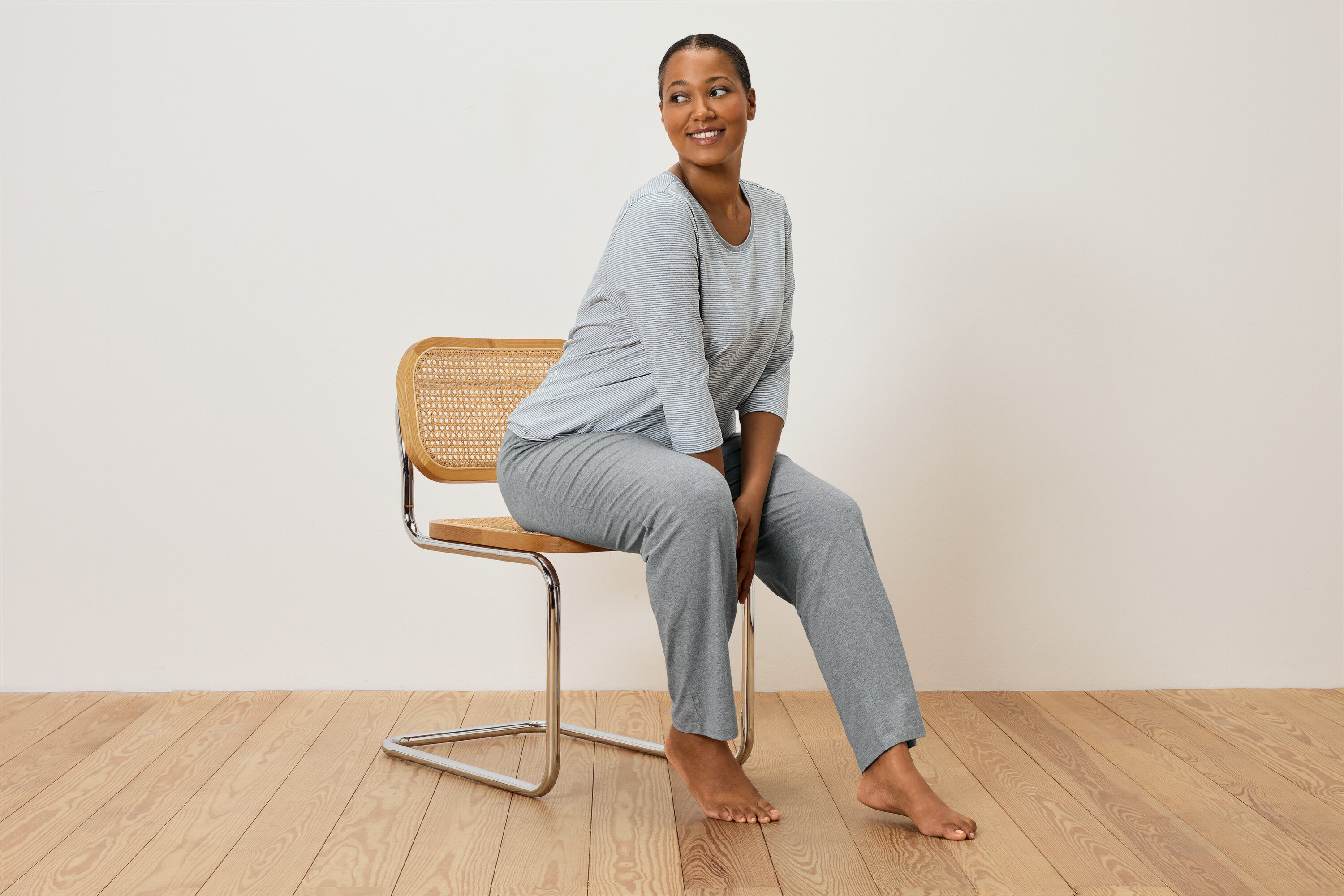 Kobieta siedzi na krześle w szarym piżamie w paski.
