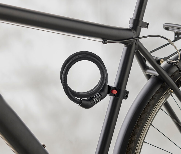 Zbliżenie czarnej ramy roweru ze spiralnym zamkiem szyfrowym przymocowanym do ramy.